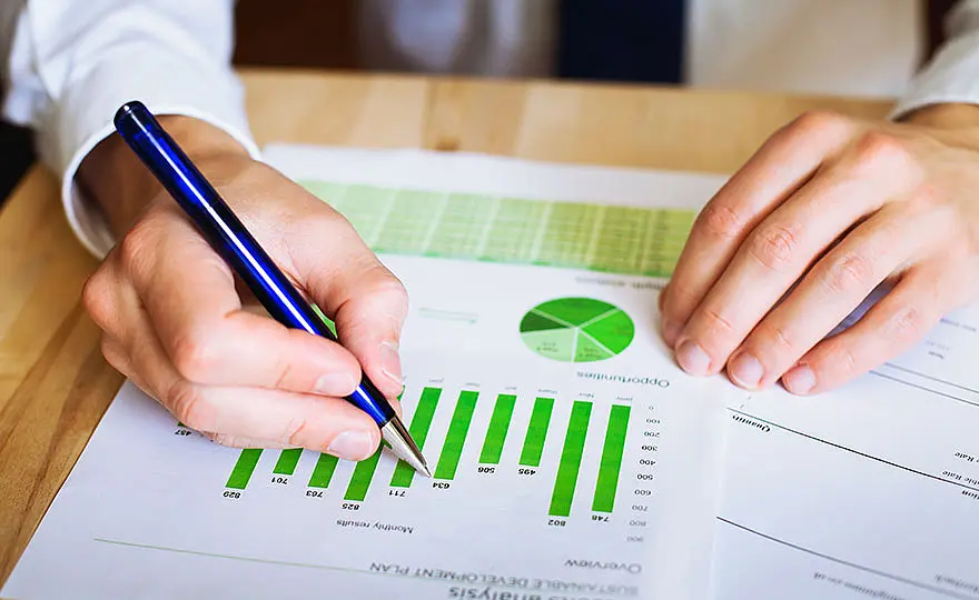 A man’s hands holding a pen whilst working on a document