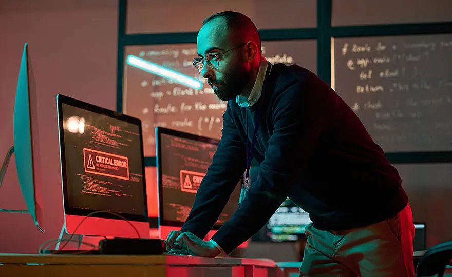 IT expert using a computer with a red error light